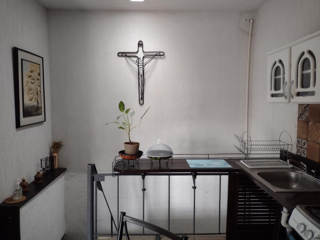 une croix suspendue sur un mur à côté d'une table dans l'établissement Loft aeropuerto, à Guatemala