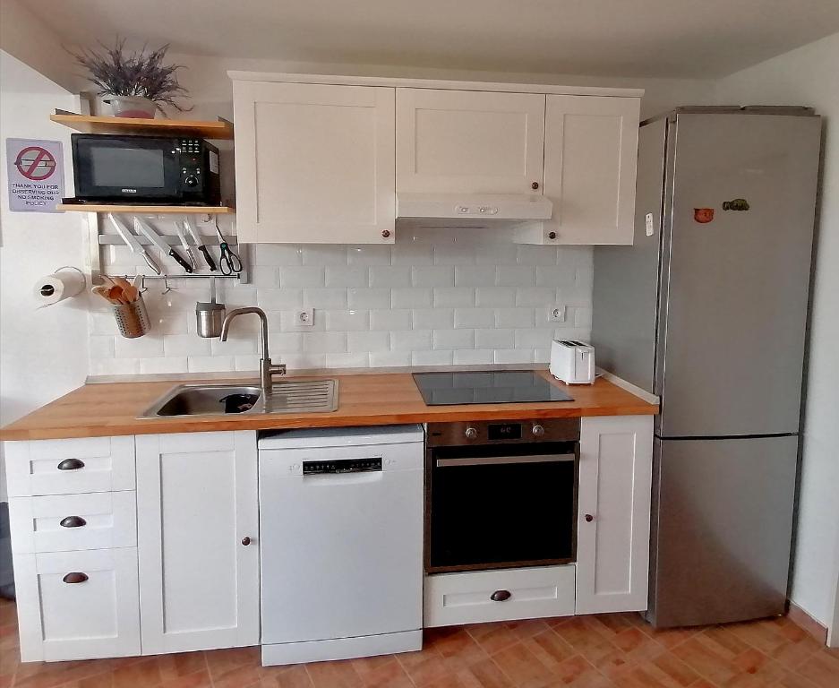 a small kitchen with white cabinets and a refrigerator at SOUL HOUSE MOKI, Primošten, Hrvaška in Primošten