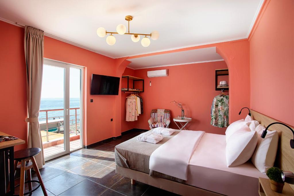 um quarto com paredes cor de laranja, uma cama e uma varanda em CONTE CRISTO Suites em Paralia Katerinis