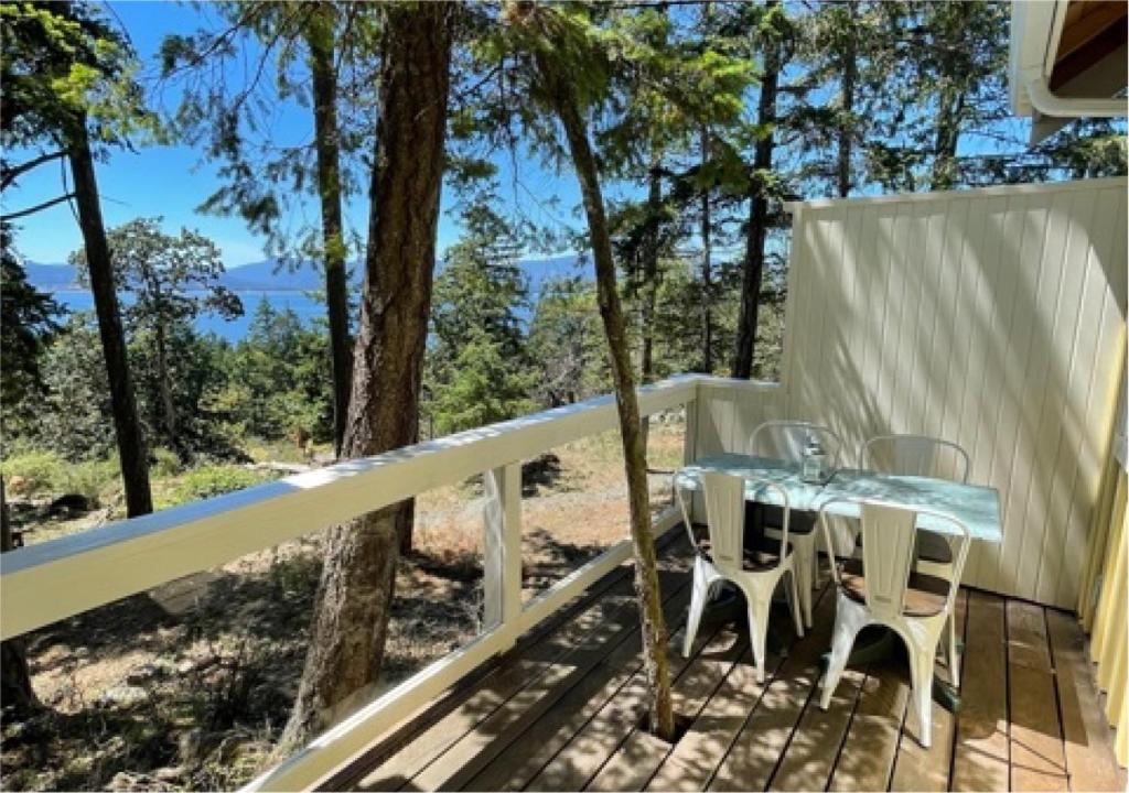 a glass table and chairs on a deck with trees at Quarrystone House B&B in Fernwood