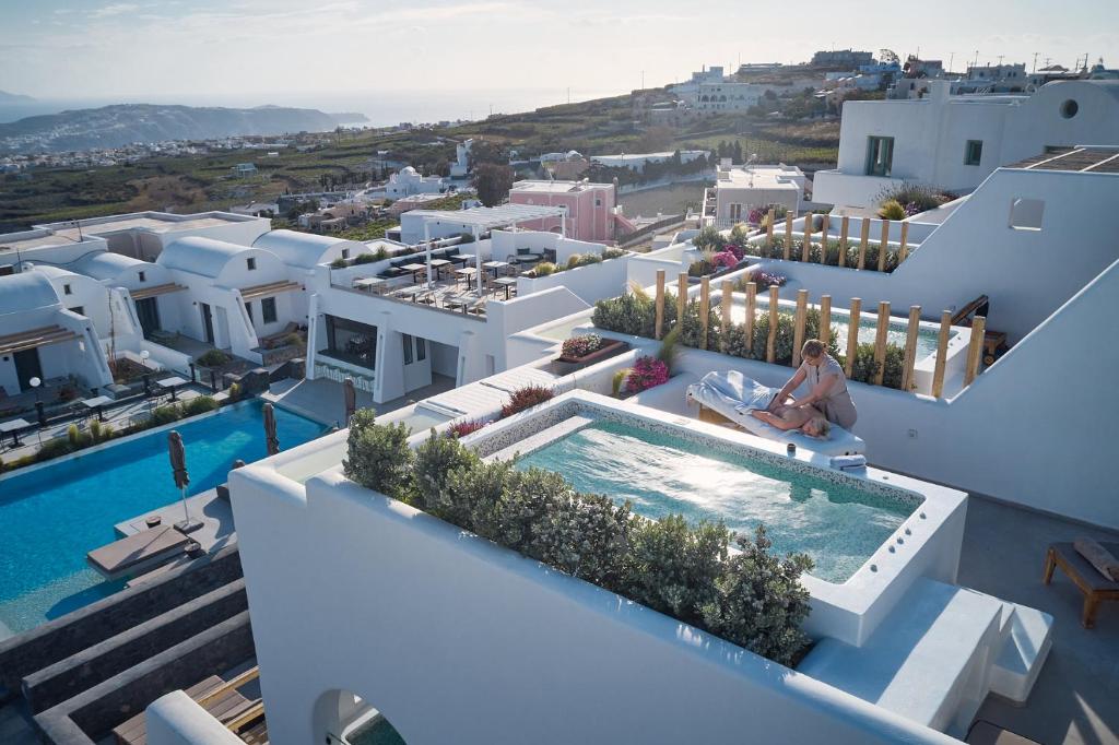 a woman sitting on the edge of a house with a swimming pool at Alleys All-Suite Hotel & Spa in Pyrgos