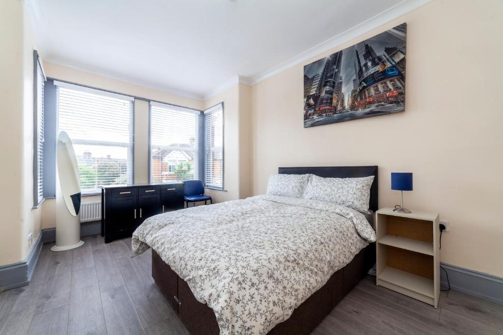 a bedroom with a bed and a large window at Highlands Gardens Suites in Ilford