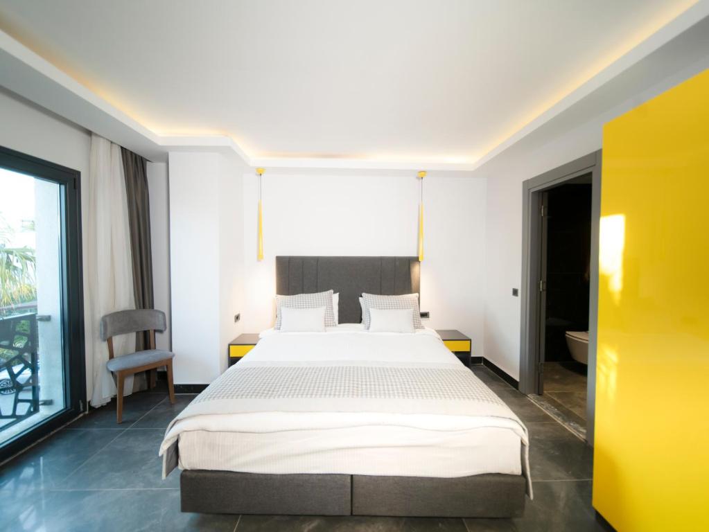 a bedroom with a large bed and a yellow wall at Sea Palm Otel Yalıkavak in Yalıkavak