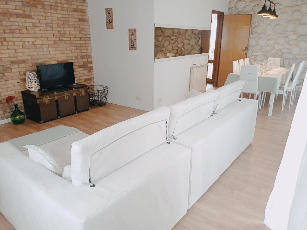 a white couch in a living room with a tv at 300 mt from the Sea - Free Parking - Wi-fi AC & Prime Video in Lido di Camaiore