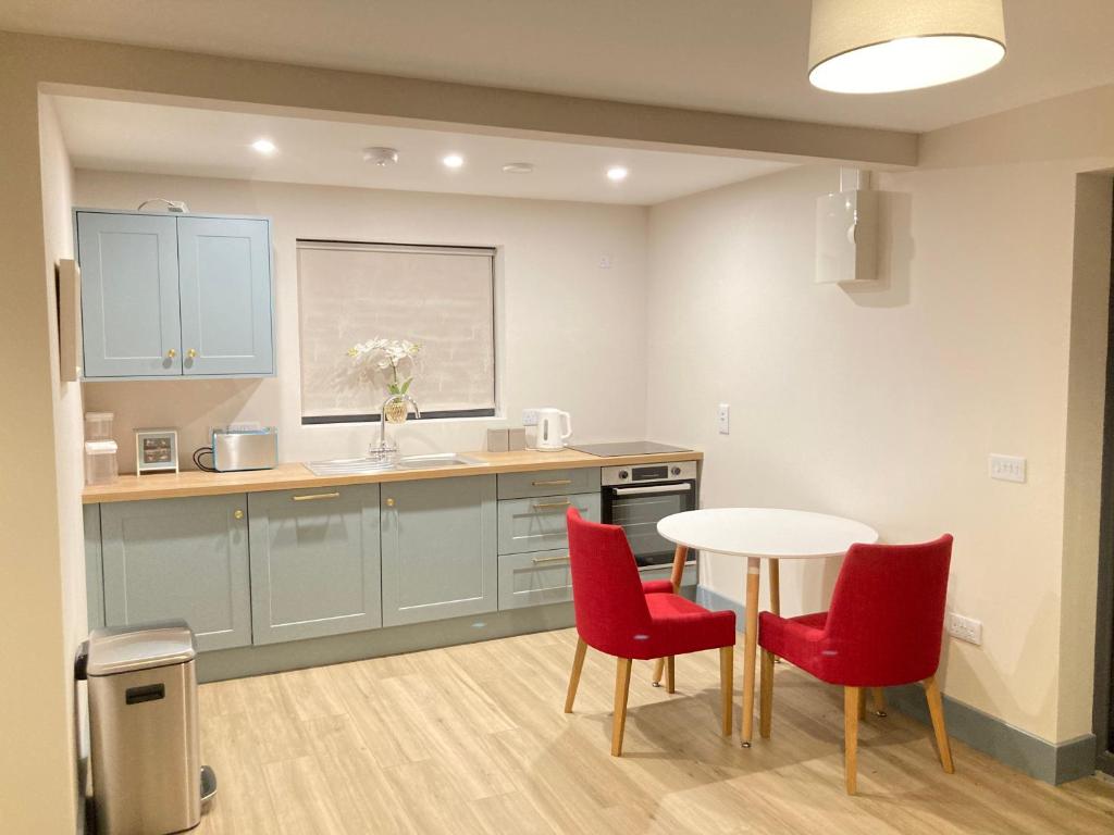 a kitchen with red chairs and a white table at Natures Rest Apartment in Doolin