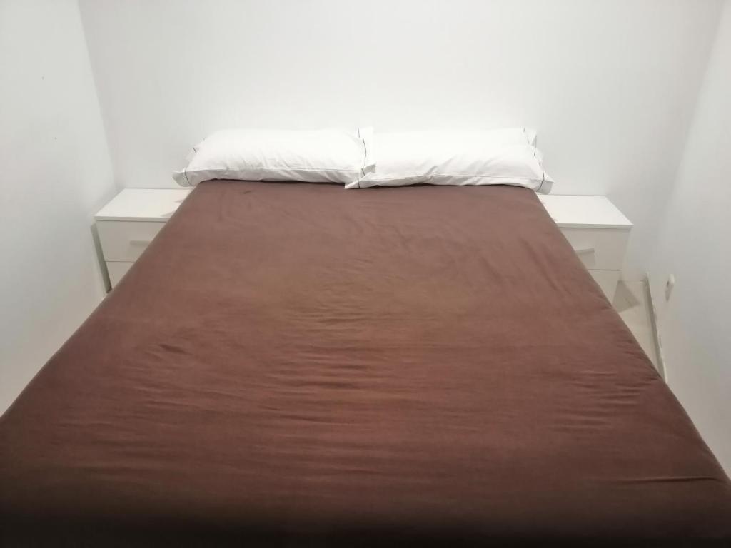 a bed with a brown bedsheet and a white pillow at Donostia Apartment Parking Included in San Sebastián