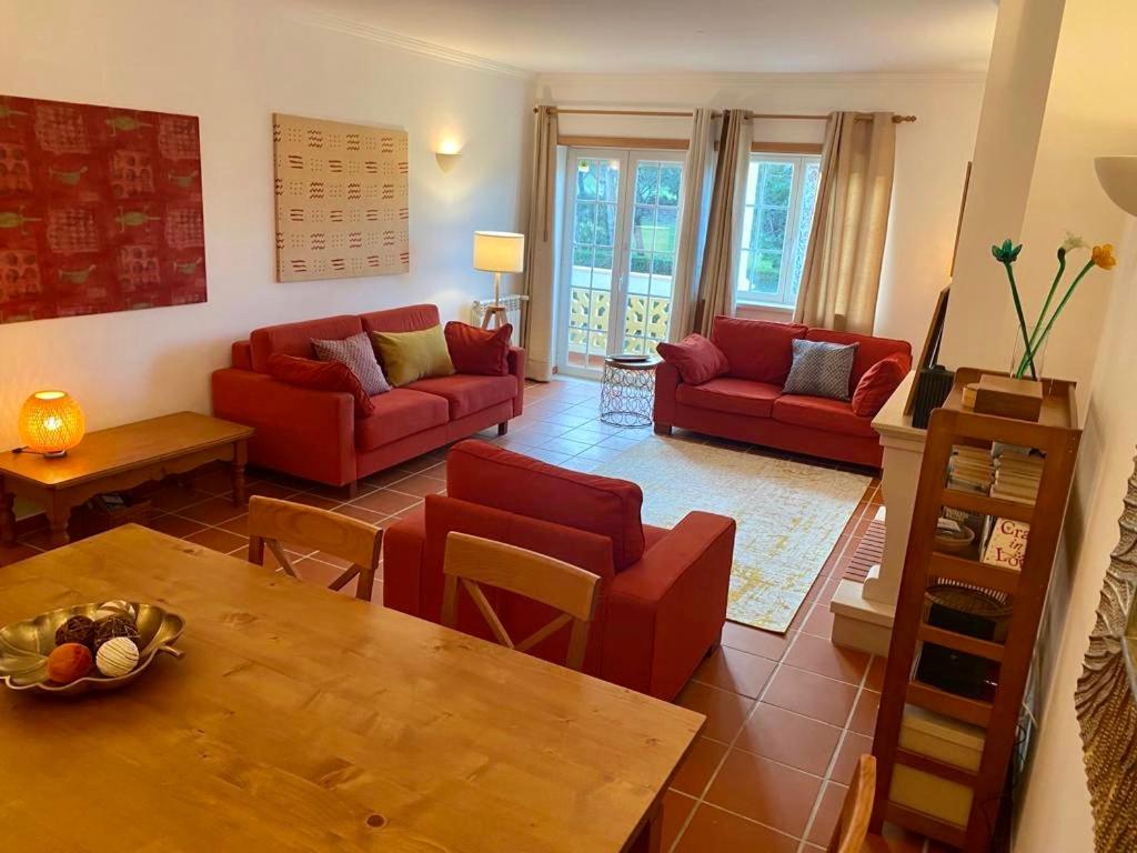 een woonkamer met rode banken en een tafel bij Golf & Praia Del Rey - Óbidos -6 hospedes in Óbidos