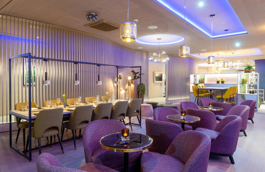 a restaurant with purple chairs and tables in a room at Leonardo Hotel Augsburg in Augsburg