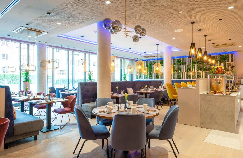 a restaurant with tables and chairs and a bar at Leonardo Hotel Augsburg in Augsburg