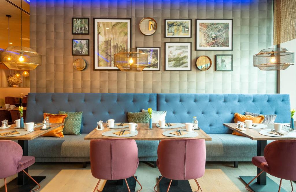 a restaurant with two tables and a blue couch at Leonardo Hotel Augsburg in Augsburg