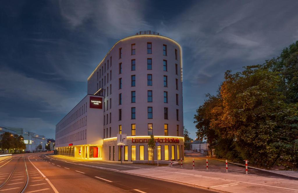 een hoog wit gebouw aan de kant van een straat bij Leonardo Hotel Augsburg in Augsburg