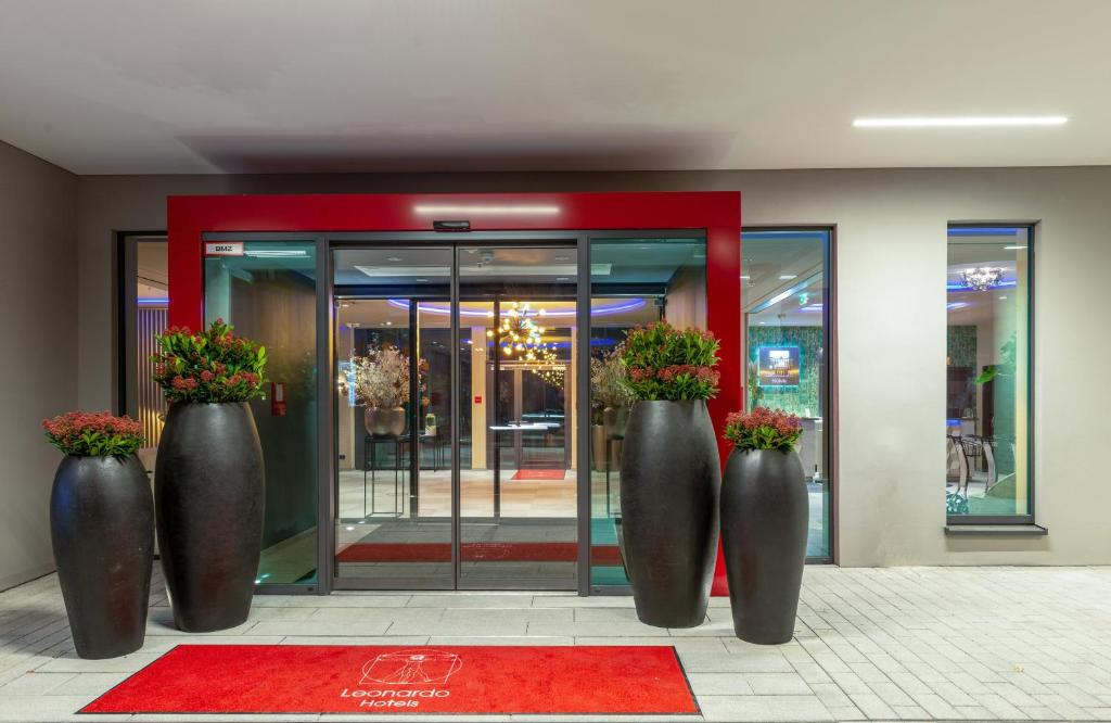 three large metal vases with flowers in front of a building at Leonardo Hotel Augsburg in Augsburg
