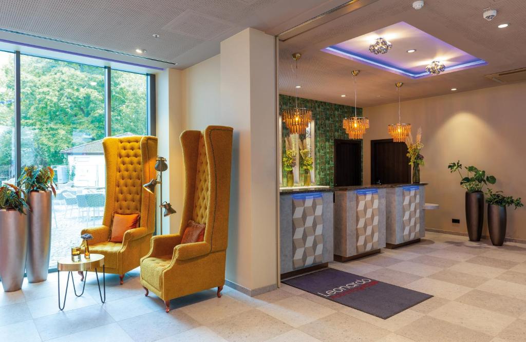 a waiting room with two chairs and a table at Leonardo Hotel Augsburg in Augsburg