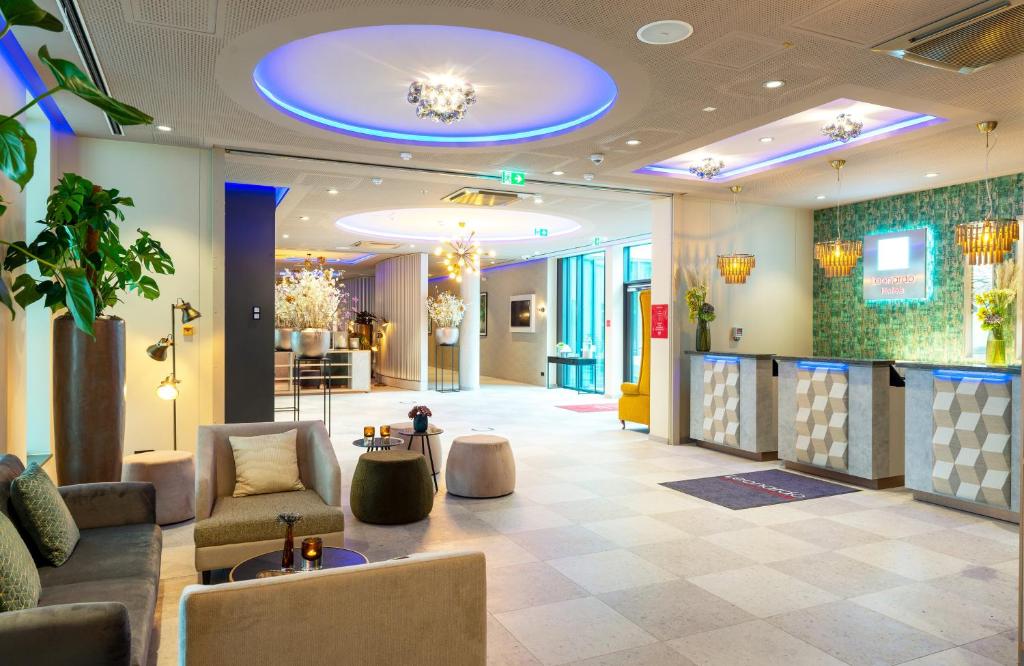 a lobby of a hotel with couches and chairs at Leonardo Hotel Augsburg in Augsburg