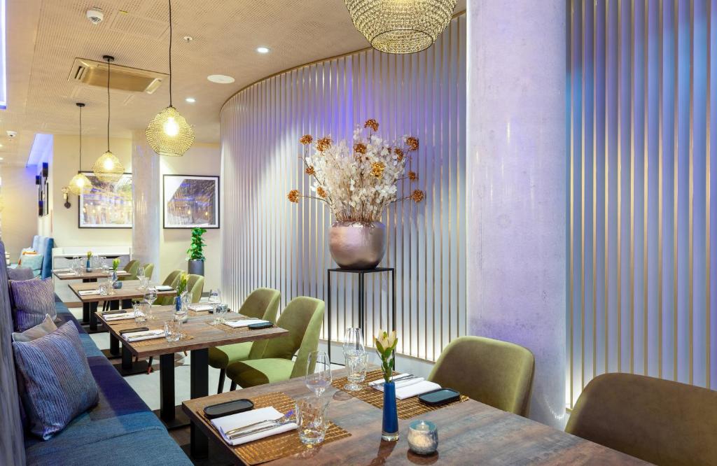 a restaurant with tables and chairs and a vase of flowers at Leonardo Hotel Augsburg in Augsburg