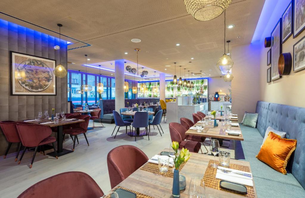 a restaurant with tables and chairs and a bar at Leonardo Hotel Augsburg in Augsburg