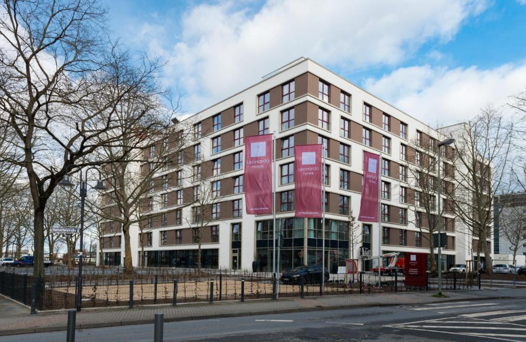 un edificio con pancartas rojas a su lado en Leonardo Hotel Offenbach Frankfurt en Offenbach