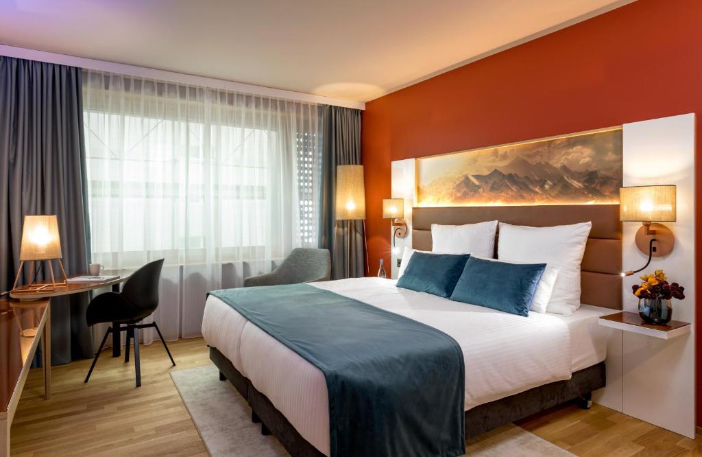 a hotel room with a bed and a desk at Leonardo Hotel Zurich Airport in Kloten