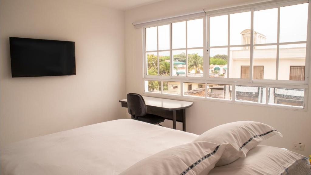 1 dormitorio con cama, escritorio y ventana en Hotel Casa Alom, en Cali