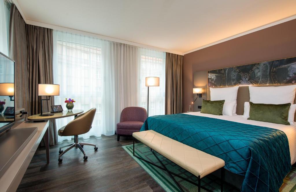 a hotel room with a bed and a desk at Leonardo Royal Hotel Nürnberg in Nuremberg