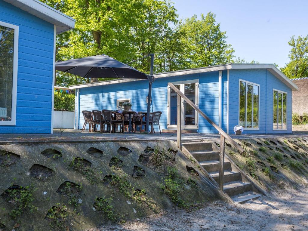 een blauw huis met een tafel en een paraplu bij Beautiful house with sandy beach near Giethoorn in De Bult