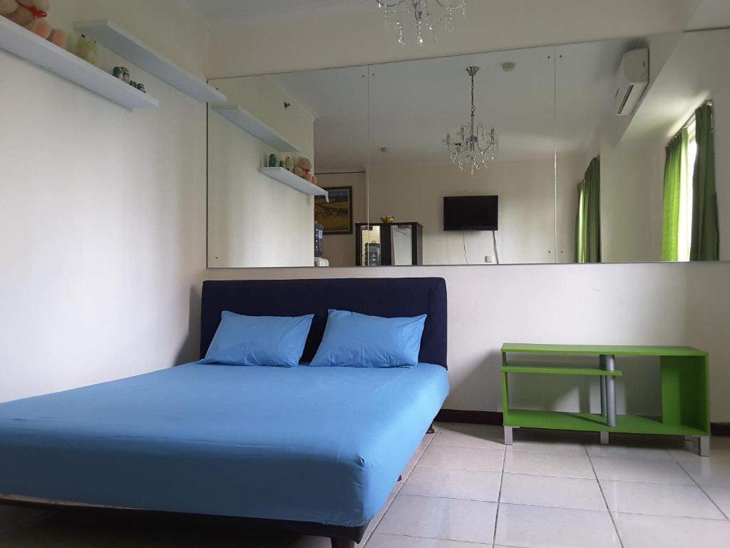 ein Schlafzimmer mit einem blauen Bett und einem grünen Tisch in der Unterkunft apartment maple park kemayoran in Jakarta