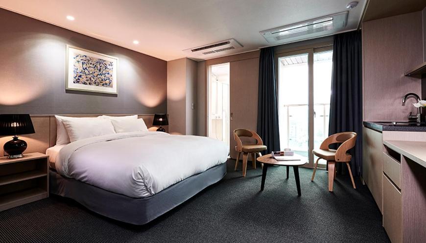 une chambre d'hôtel avec un lit et une cuisine dans l'établissement New Raon Stay, à Jinju