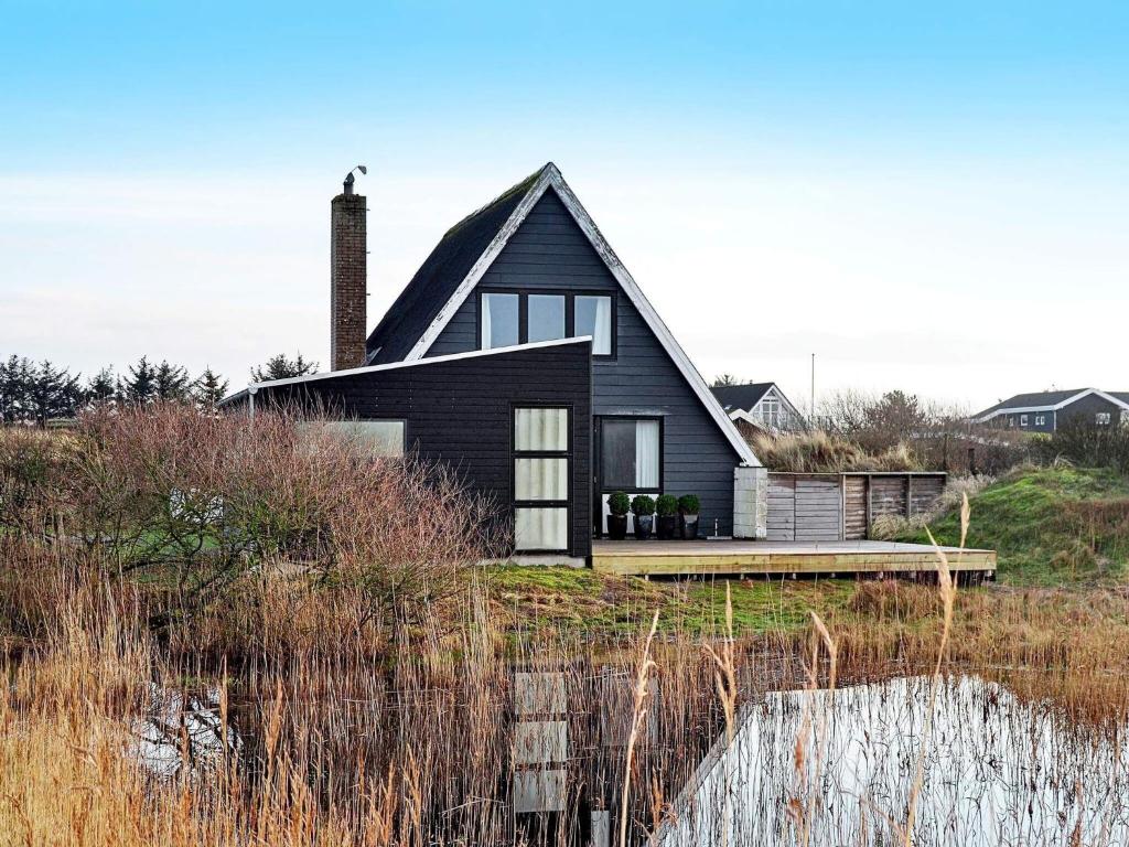 a black house on the shore of a body of water at 5 person holiday home in Fan in Fanø