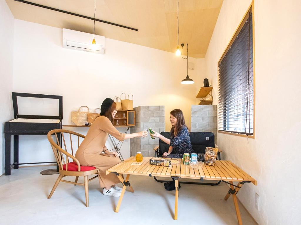 duas mulheres sentadas numa mesa numa sala em LifeStyleHotel ichi一棟貸切りホテル em Kochi