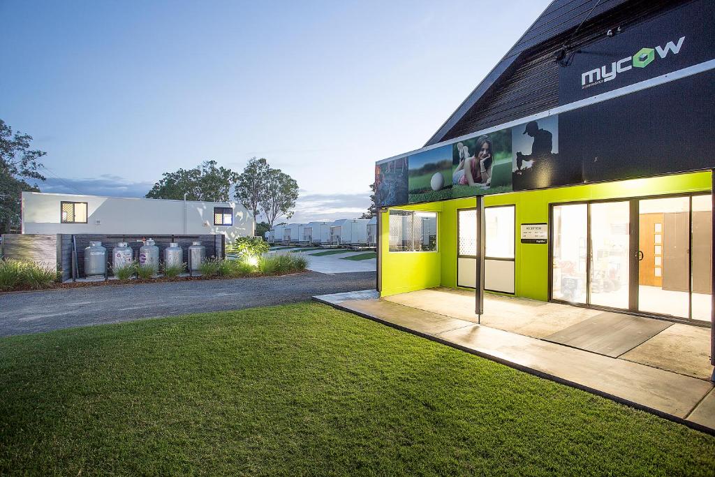 a yellow and black building with a grass yard at Mycow Accommodation Mackay in Mackay