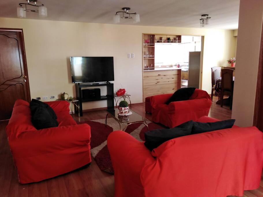 een woonkamer met rode stoelen en een flatscreen-tv bij Departamento REKADI in Cuzco