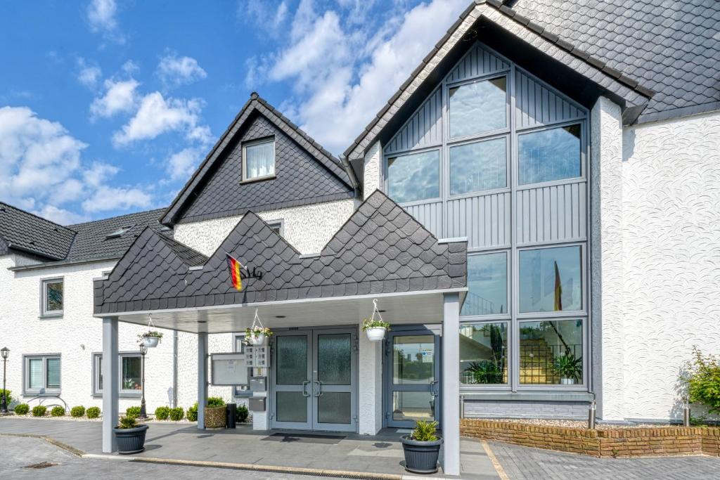 a white house with a black roof at Hotel Seeblick Försterhaus in Owschlag