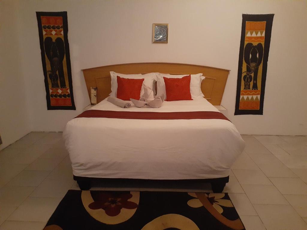 a bedroom with a large bed with red pillows at Sunshinevibe guest house in Kasane