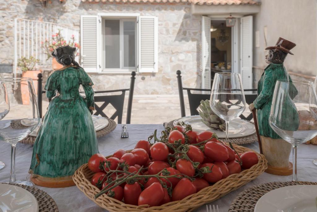 twee standbeelden van vrouwen aan een tafel met een kom tomaten bij Casa delle sirene in Letojanni