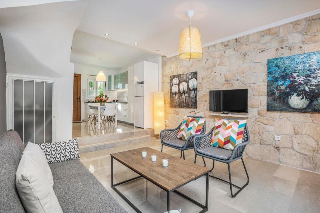 a living room with a couch and chairs and a tv at Boutique Maisonette in Pefkohori