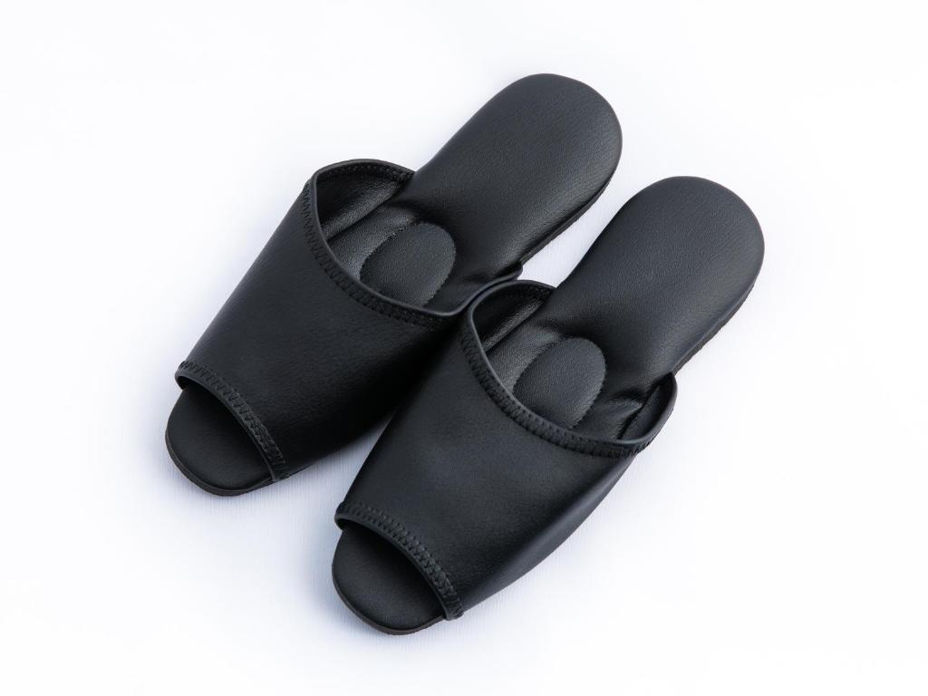 a pair of black slippers on a white background at APA Hotel Haneda Anamori Inari Ekimae in Tokyo
