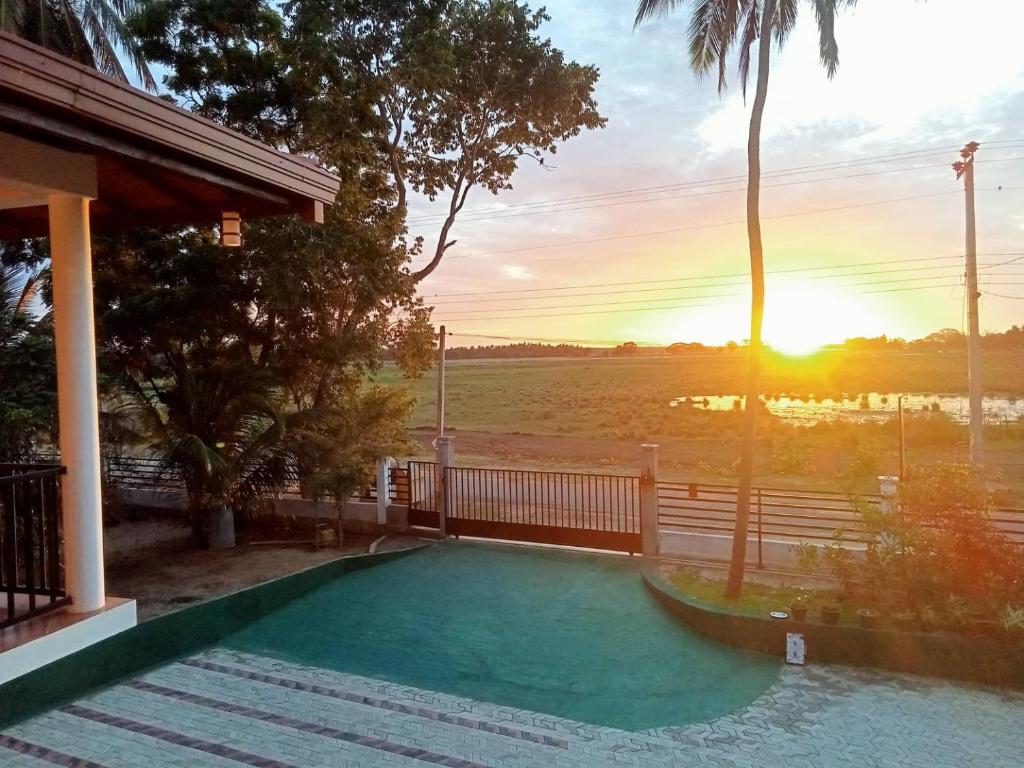 a house with a swimming pool with the sunset in the background at Double Lake View Tissa & Safari in Tissamaharama