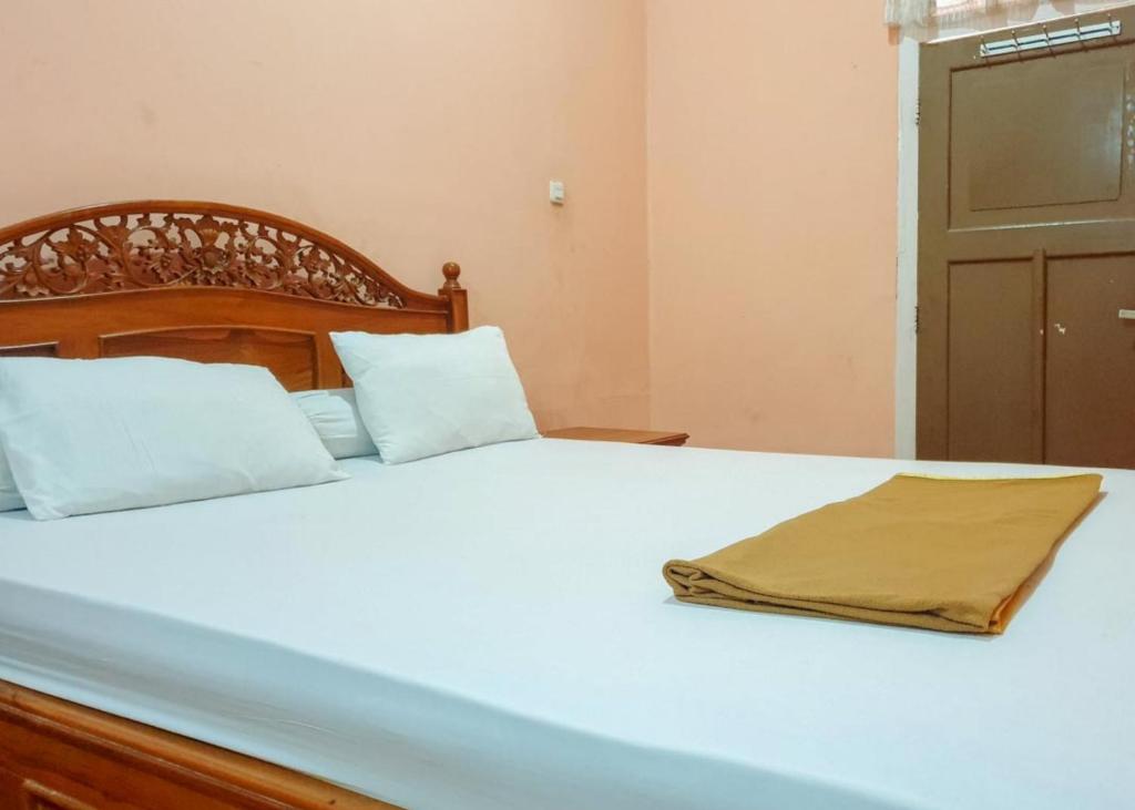 un letto con lenzuola bianche e una coperta sopra di Hotel Mario Pulana Bone a Watampone