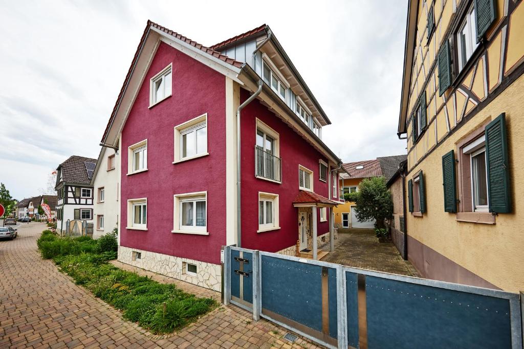 a red house with a fence next to some buildings at Wohnung 22 - Auszeit - nur 5 Minuten vom Europa-Park in Kappel-Grafenhausen