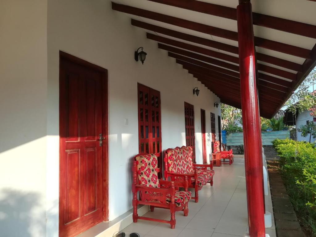 a row of red chairs sitting on a porch at Sun & Sand Guest House in Mullaittivu