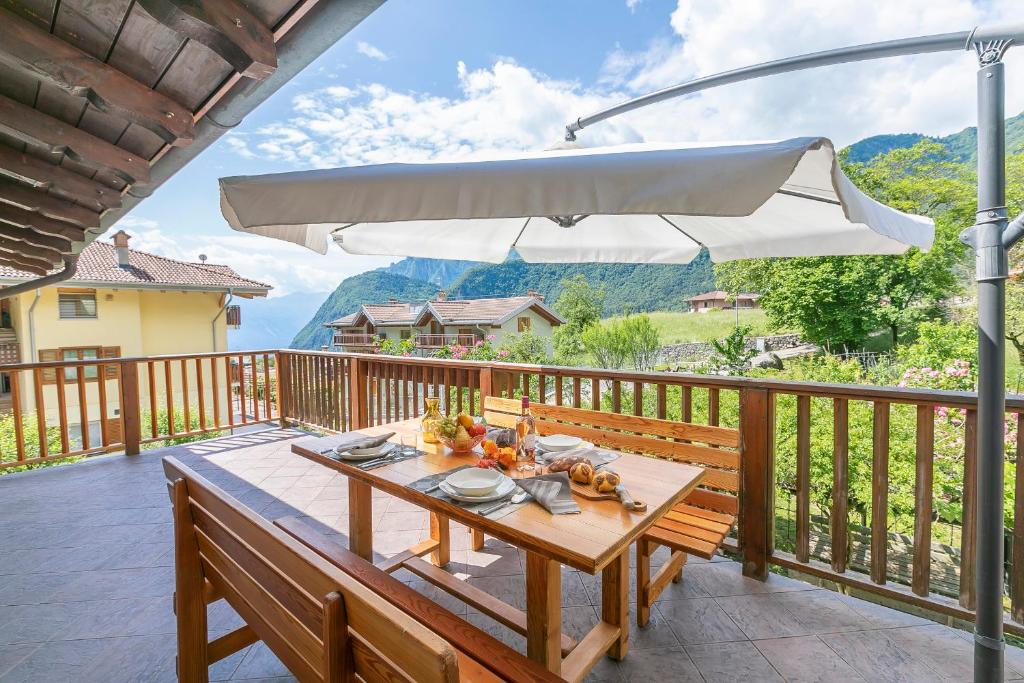 une table en bois sur une terrasse avec un parasol dans l'établissement Casa Tra Borgo e Lago, à Tenno
