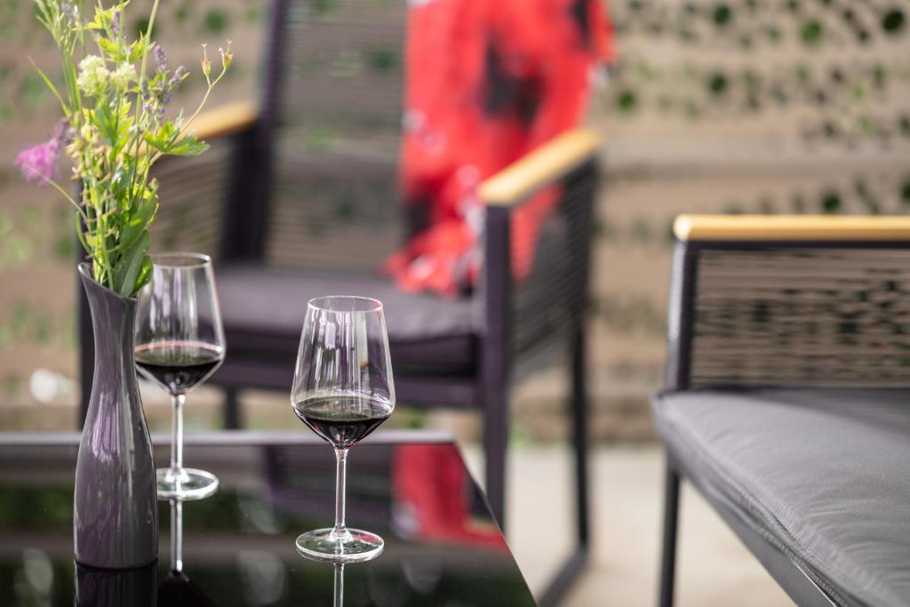 two wine glasses on a table with a vase of flowers at Pannonia Appartements 2 in Neusiedl am See