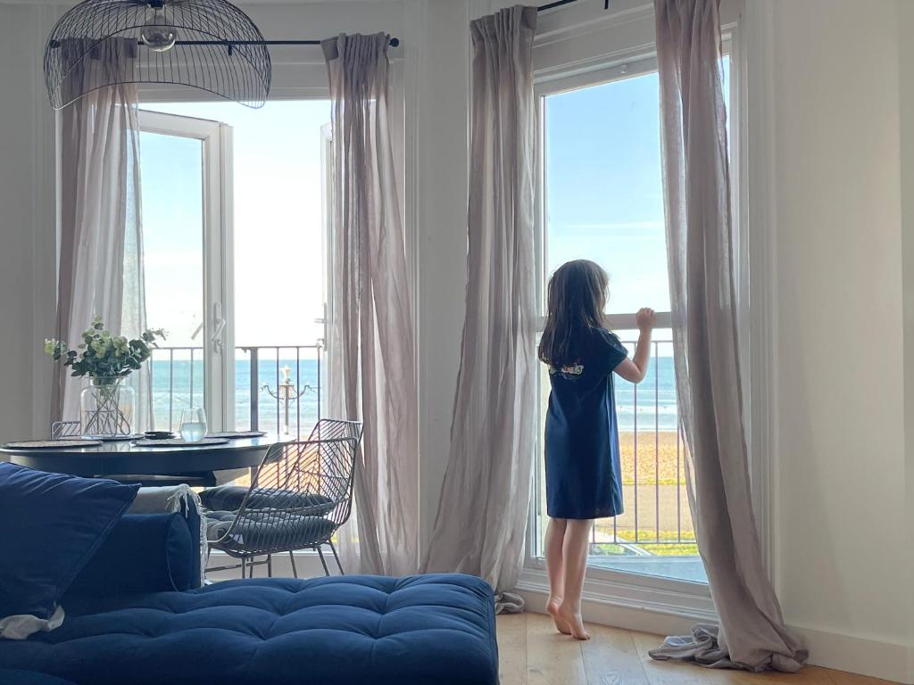 a girl looking out of a window at the ocean at Seaview flat with balcony, spacious 2 bedroom in Worthing