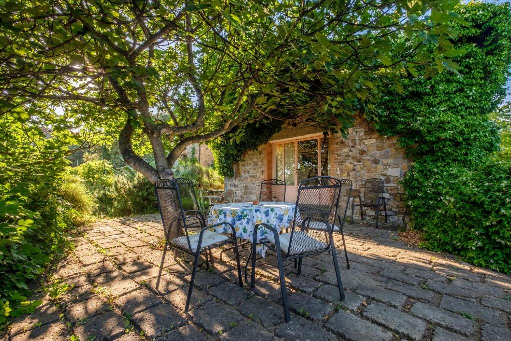 einen Tisch und Stühle unter einem Baum vor einem Haus in der Unterkunft Stella Sud Podere Carbone in Grosseto