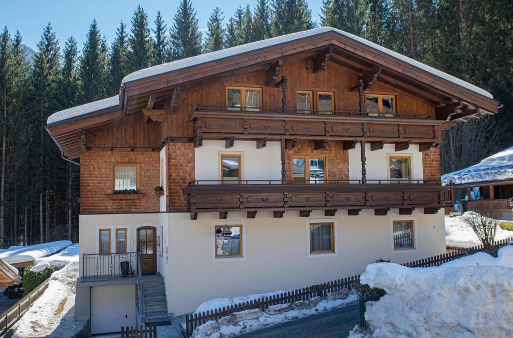 a large wooden house with a balcony in the snow at Appartment Lechner in Neukirchen am Großvenediger