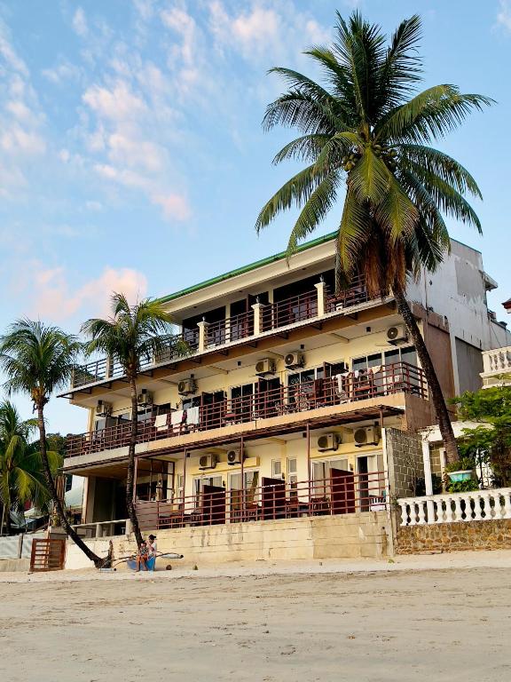 un edificio sulla spiaggia con una palma di Rosanna's Pension a El Nido