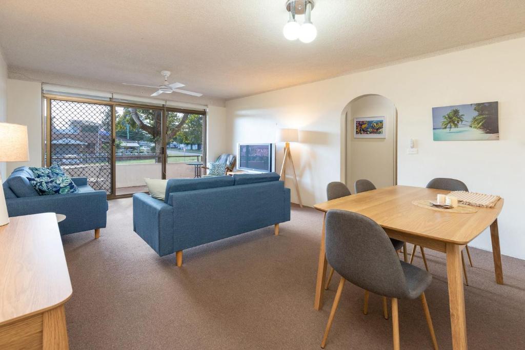 sala de estar con mesa y sofá azul en Seahorse 4 en Tuncurry