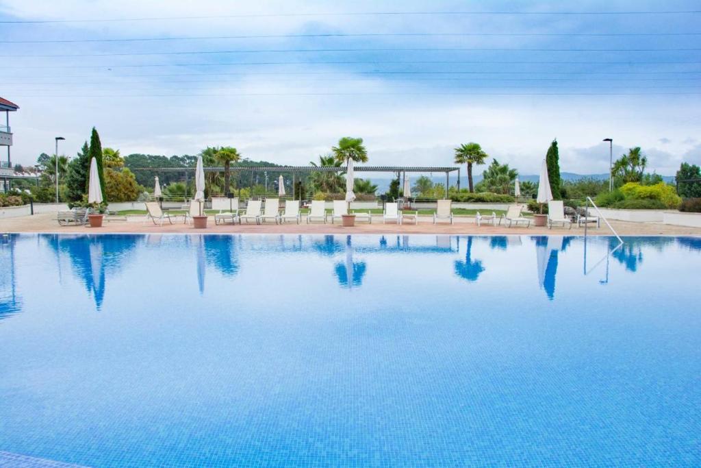 uma grande piscina com cadeiras e água azul em URBANIZACIÓN ILLAS ATLANTICAS-PORTONOVO em Sanxenxo