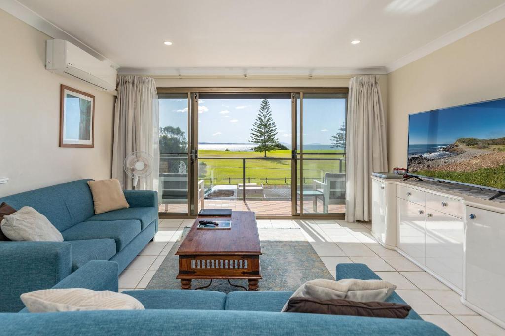 a living room with a blue couch and a table at Surfspray 3 Pebbly Beach in Forster
