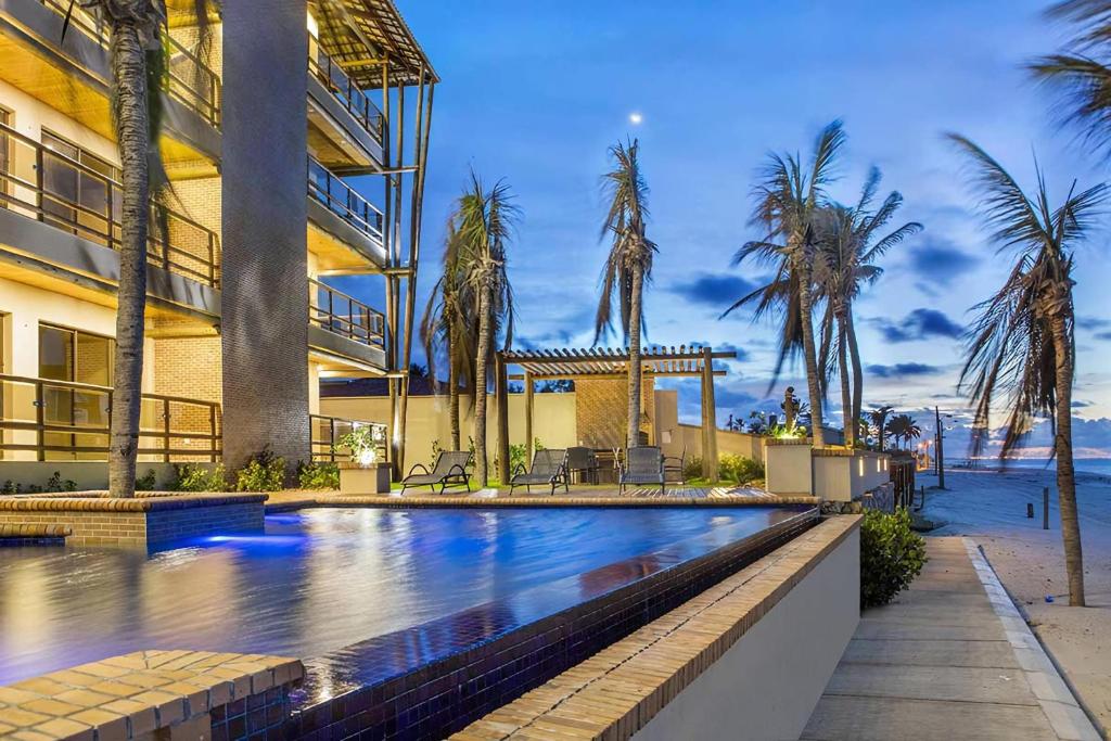 una piscina frente a un edificio con palmeras en Varandas Do Mar Modern Deluxe Apartment Beach Front Cumbuco, en Cumbuco